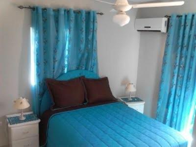 um quarto com uma cama azul com cortinas azuis em Blue Acuarela em Cabrera