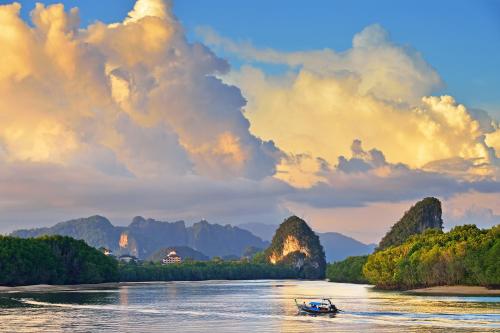 a boat on a river with mountains in the background at Krabi Home Town Boutique in Krabi town