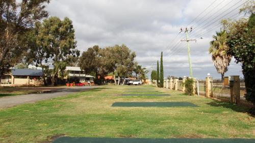 a grassy road with a fence and trees on it at Australind Tourist Park in Australind