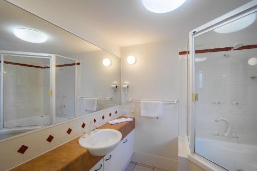 a white bathroom with a sink and a shower at Kings Row Apartments in Caloundra