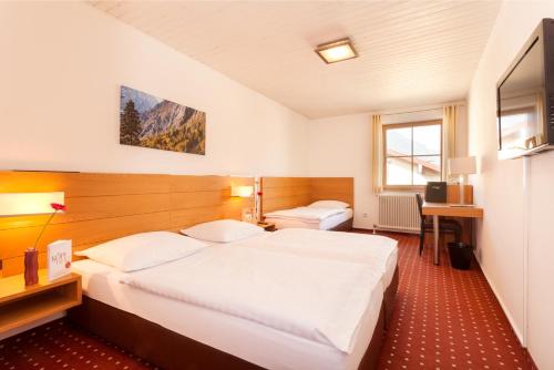 ゴリング・アン・デア・ザルツァッハにあるホテル ペンション ゴーリンゲンのベッド2台とデスクが備わるホテルルームです。