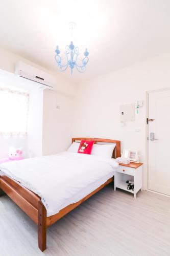 a white bedroom with a bed and a chandelier at Long house in Taichung