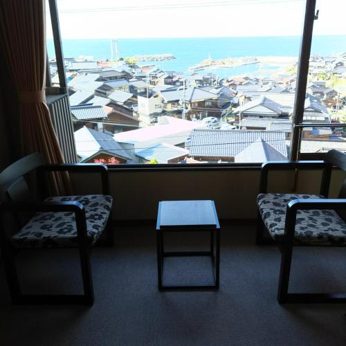 a room with two chairs and a table in front of a window at Shorenkan Yoshinoya in Kyotango