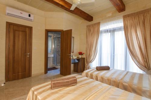 a hotel room with two beds and a window at Carini Farmhouses in Għarb