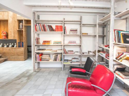 a red chair in a room with bookshelves at Uma Sapna Seminyak in Seminyak
