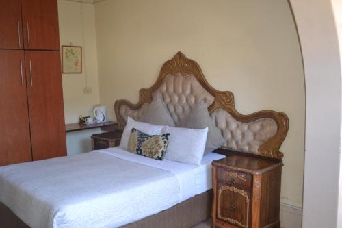 una camera da letto con un letto grande con testiera in legno di oasis guest house a East London