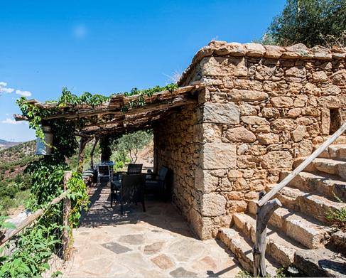 a stone building with a table and chairs in it at Les Bergeries "Le figuier" in Omessa