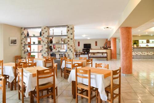 a restaurant with tables and chairs in a room at Hotel Eleana in Agios Ioannis Pelio
