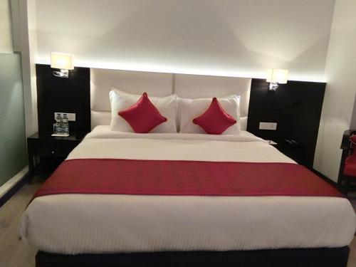 a bedroom with a large bed with two red pillows at Ramada Encore Jalandhar in Jalandhar