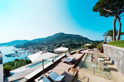 a pool with chairs and a view of the water at San Montano Resort & Spa in Ischia