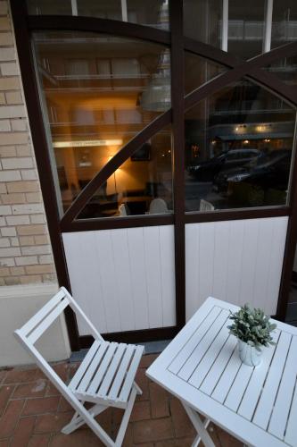 two white chairs and a table and a potted plant at Het Koetshuis, op 50m van zee, voor 5 personen, centrum Westende BAD, alle comfort in Middelkerke