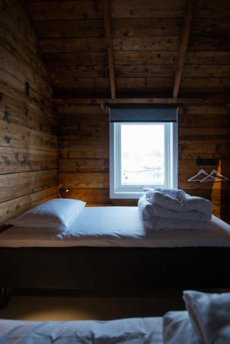a bed in a wooden room with a window at Hattvika Lodge in Ballstad