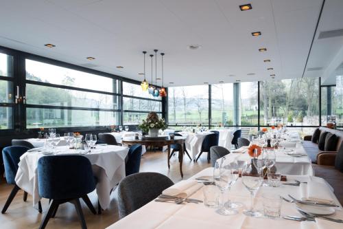 a restaurant with white tables and chairs and large windows at Bilderberg Kasteel Vaalsbroek in Vaals