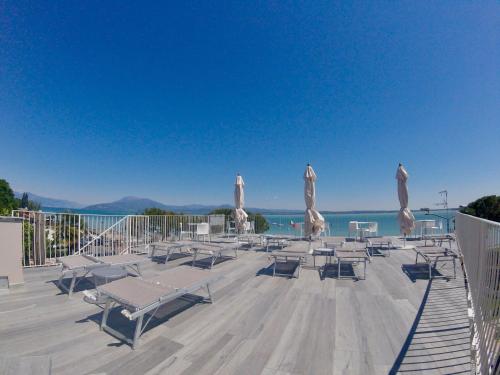 a group of chairs and umbrellas on a deck at Hotel Ca' Serena in Sirmione