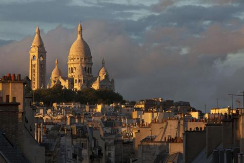 uma vista para uma cidade com edifícios e uma torre do relógio em Cote Montmartre em Paris