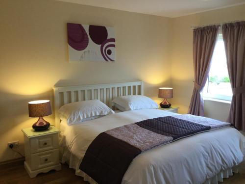 a bedroom with a bed with two lamps and a window at Atlantic Breeze in Rossnowlagh