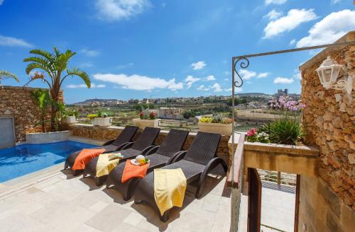 un patio con un montón de sillas y una piscina en Carini Farmhouses en Għarb