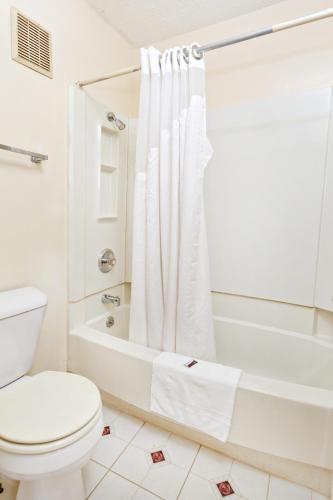 a white bathroom with a toilet and a bath tub at Red Carpet Inn - Louisville in Louisville