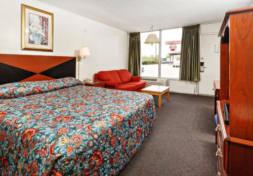 a hotel room with a bed and a chair at Red Carpet Inn - Louisville in Louisville