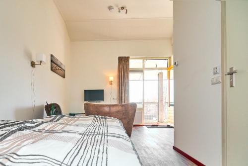 a bedroom with a bed with a chair and a window at Tussen de Diepen in Blokzijl