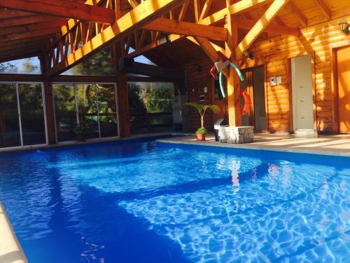 a swimming pool in a house with a wooden ceiling at Encanto del Rio in Villa La Angostura