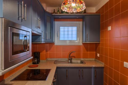 een keuken met blauwe kasten, een wastafel en een raam bij Sunset in Icod de los Vinos