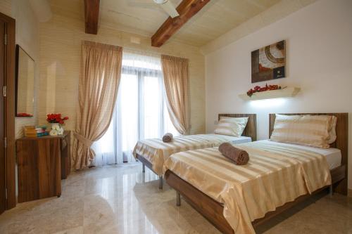a bedroom with two beds and a window at Carini Farmhouses in Għarb