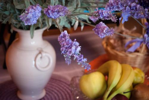 een witte vaas met paarse bloemen en fruit op een tafel bij Amarcord in Bagnoregio