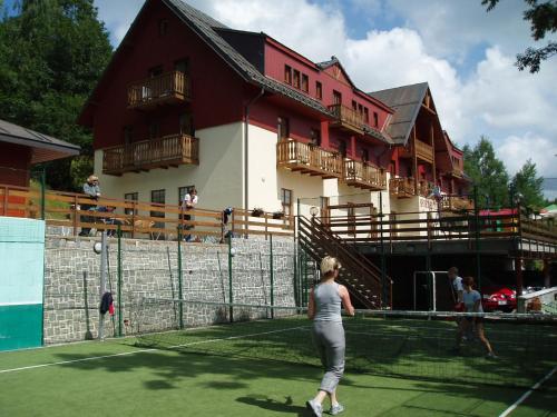 a woman standing on a tennis court in front of a building at Svycarska Bouda in Špindlerův Mlýn