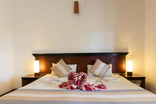 a bed with two pairs of striped socks on it at The Coconut Gardens Hotel & Restaurant in Tissamaharama