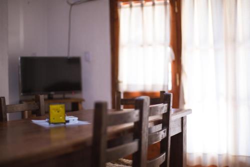 a dining room with a table and a television at Carü Leufu in Valle Grande