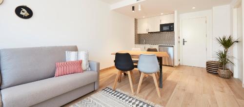 a living room with a couch and a table and chairs at Apartahotel Dos Ríos Ainsa in Aínsa