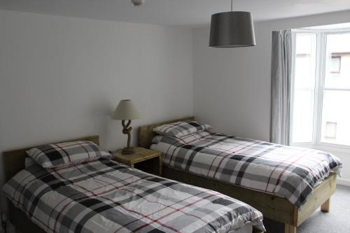 two twin beds in a room with a window at The Pier Hotel in Aberystwyth