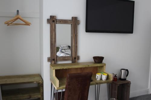 a room with a tv and a wooden shelf at The Pier Hotel in Aberystwyth