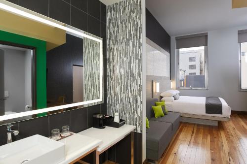 a bathroom with a bed and a sink and a mirror at CityFlatsHotel - Grand Rapids, an Ascend Collection Hotel in Grand Rapids
