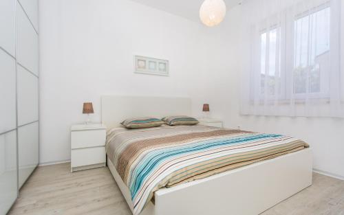 um quarto branco com uma cama e uma janela em Apartman Iva em Šilo