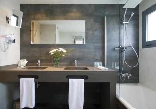 a bathroom with a sink and a mirror and a shower at Hotel Spa Niwa in Brihuega