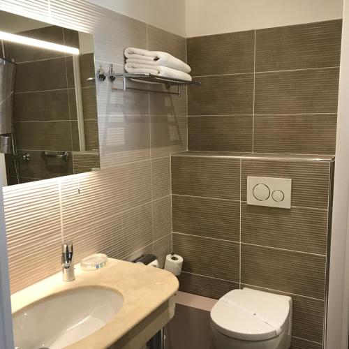 une salle de bain avec un lavabo et des toilettes dans l'établissement Grand Hotel Moriaz, au Lavandou