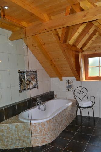 a bath tub in a room with a chair at Enço deth terralh in Pierrefitte-Nestalas