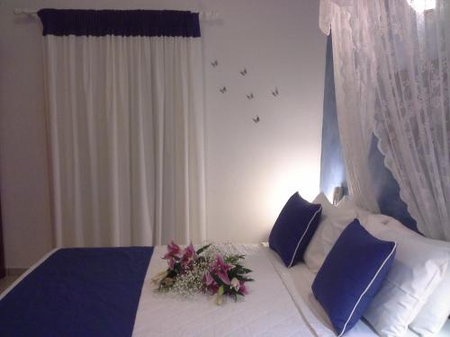 a bedroom with a bed with blue pillows and flowers on it at Kiklamino Sunset Studios in Oia