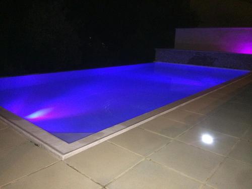- une piscine avec éclairage violet dans une maison dans l'établissement La Paillote Exotique Spa, à Beaucaire