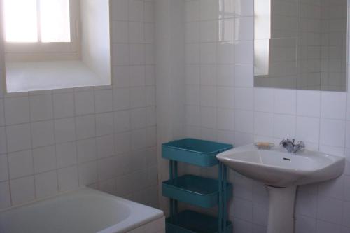 Baño de azulejos blancos con lavabo y bañera en Le Petit Carpia, en Castillon-de-Castets