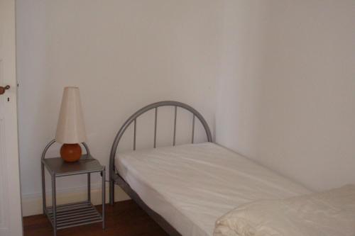 1 dormitorio con cama y mesita de noche con lámpara en Le Petit Carpia, en Castillon-de-Castets