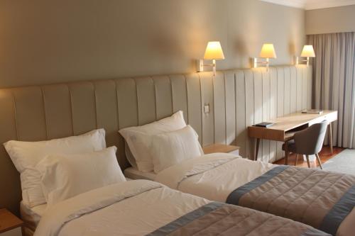 a hotel room with two beds and a desk at Hotel Suave Mar in Esposende