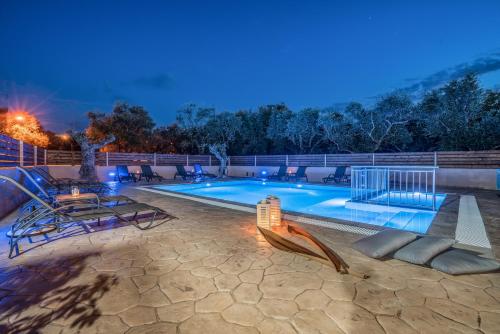 uma piscina à noite com cadeiras e uma mesa em Armonia Boutique Hotel em Méson Yerakaríon