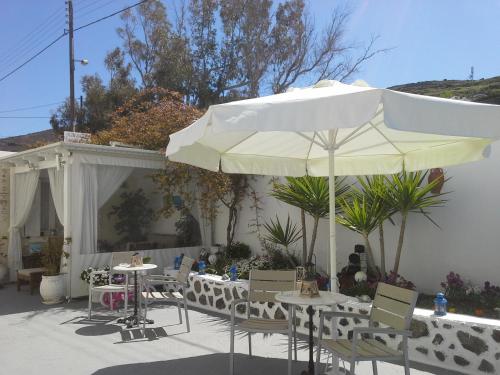 a patio with tables and chairs and an umbrella at Kiklamino Sunset Studios in Oia