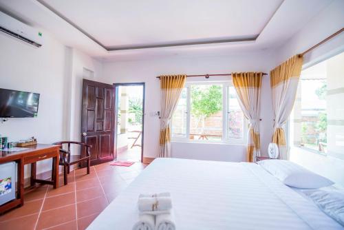 a bedroom with a bed and a desk and window at Trung Huynh Bungalow in Phu Quoc