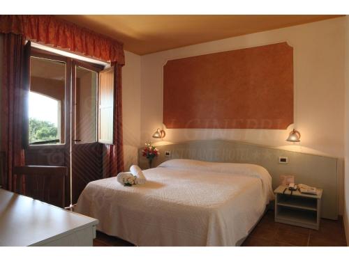 a bedroom with a bed with a teddy bear on it at Hotel I Ginepri in Quartucciu