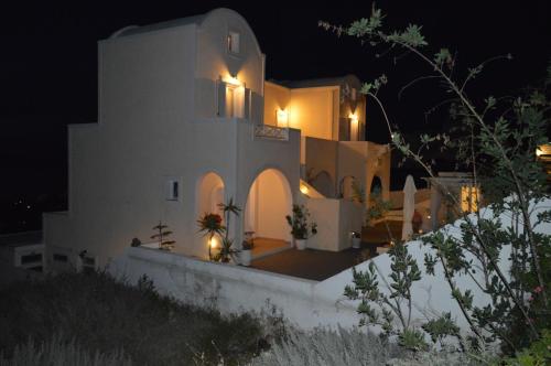 a house with lights on the side of it at night at Kiklamino Sunset Studios in Oia