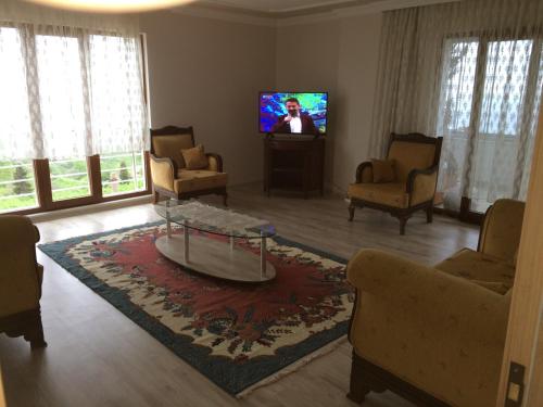 a living room with a tv and a table and chairs at Menekşe Apart 2 in Trabzon